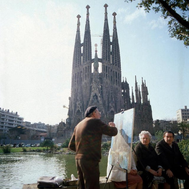 This vibrant photograph captures a moment in front of the Sagrada Família in Barcelona during the 1960s. The majestic...