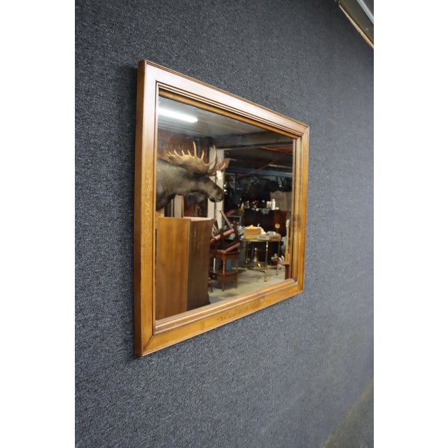 American Hitchcock maple framed wall mirror with a warm honey-toned finish and decorative floral detailing. The...