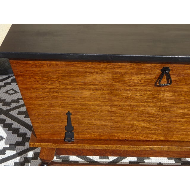 A chest of drawers-style storage unit, a rolling trunk with a wide front opening. Vintage-style furniture in oak and black...