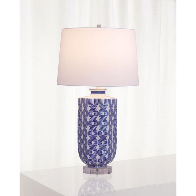 White porcelain with blue graphic woven design by Port 68. Sits atop a lucite base and finished with a white hardback...