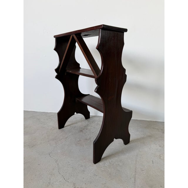 Elegant antique Italian library step stool crafted from solid dark mahogany wood, featuring a sculptural silhouette with...