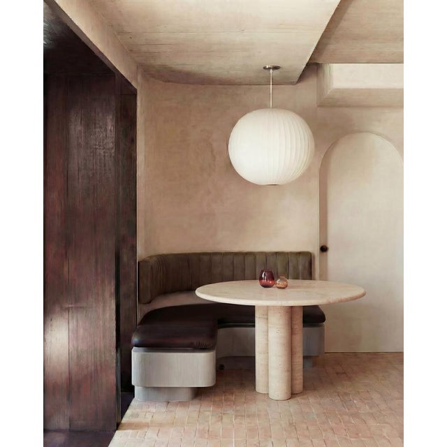 This minimalist table is made from solid travertine, featuring a circular table top with a curved edge that elegantly sits...