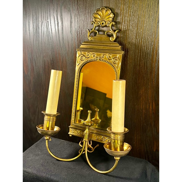 Vintage Brass Double Arm Hardwired Wall Sconce With Mirror. Traditional scallop motif at top. Tinted yellow mirrored...