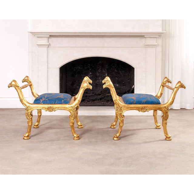 A whimsical pair of Mid-Century Giltwood Italian Curule stool benches crafted in the Neoclassical-Empire taste. The stools...
