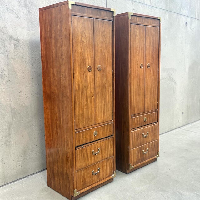 A beautiful pair of tall cabinets in the campaign style. Walnut veneers with brass mounts and hardware. Made by...