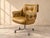 Low and round-backed, this pair of mid-century modern swivel chairs is upholstered in a tan leather look with button...