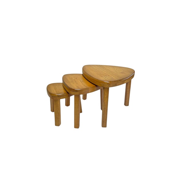 A set of three nesting tables in a warm color solid oak, oval/kidney shaped in the style of Pierre Chapo,ca 1970. Useful,...