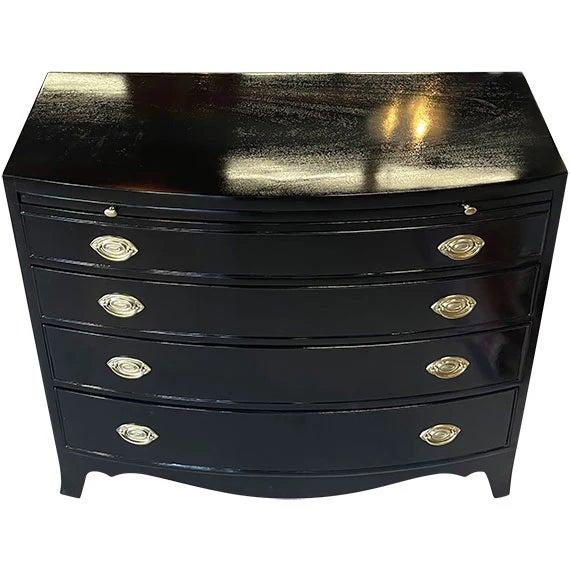 A dark-toned storage piece with a gently curved front and multiple horizontal compartments. Subtle metallic accents...