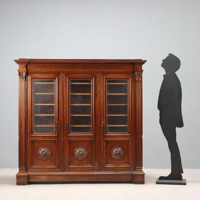 Neo-Renaissance-style walnut bookcase. Three-door front with glass top and lower panel with carved rosette. Gouged...
