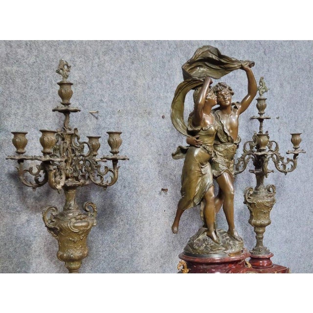 A spectacular three-piece mantel clock set, comprising a large clock with a sculpted group and two matching candelabra, in...