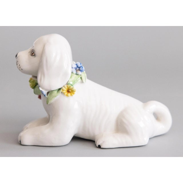 A charming petite vintage Italian white majolica dog figurine with a lovely flower wreath around its neck, circa 1950....