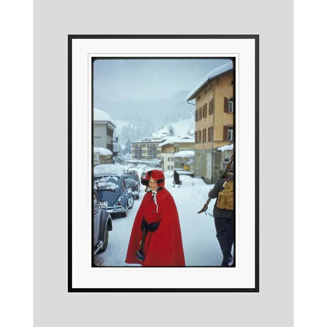 Red Riding Hood 1959 by Toni Frissell A woman dressed in a hooded red cape walks through a ski resort in winter, 1959....