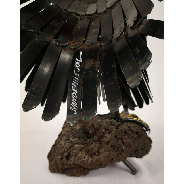 Figure of an eagle, made of metal sitting on a lava stone by the artist J. van den Heuvel. The figure can be free-...