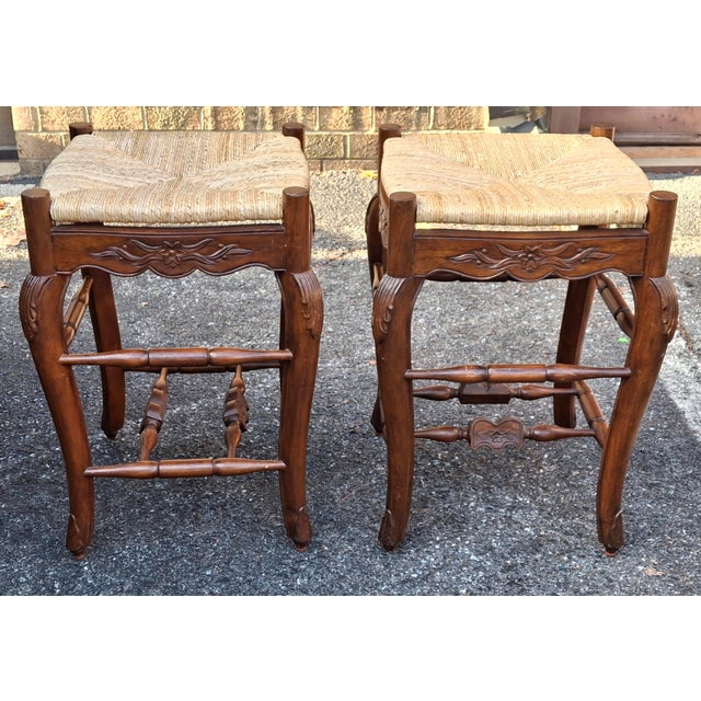 A Gorgeous Pair of Louis XV Style Carved and stained Mahogany and Rush Seat Counter Stools featuring double Stretcher for...