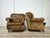 An elegant pair of vintage armchairs with a soft, enveloping design, featuring rounded armrests, a tufted backrest, and...