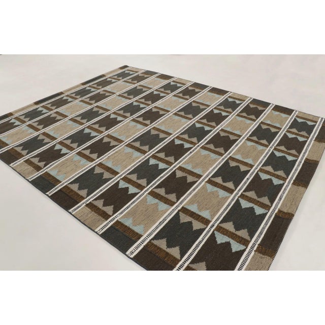 Handwoven in wool, this 8x10 Scandinavian rug features a rhythmic geometric design in warm brown, ivory, charcoal, and...