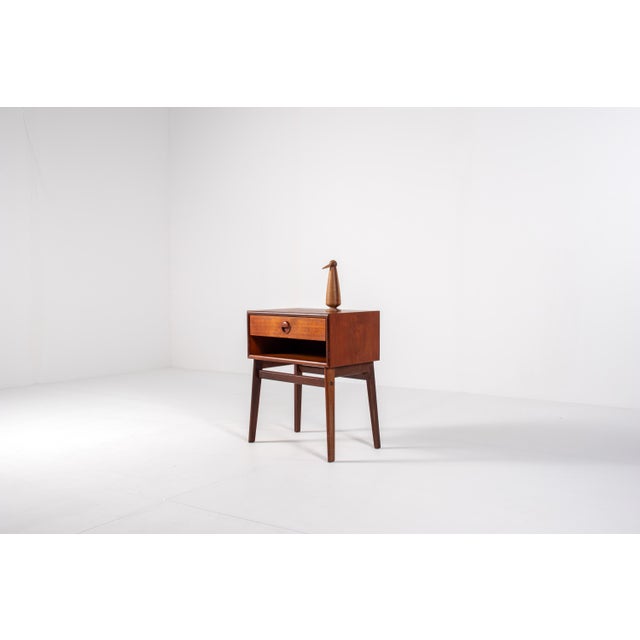 A charming mid-century bedside table in teak, crafted in Denmark in the 1960s. This elegant piece features a single drawer...
