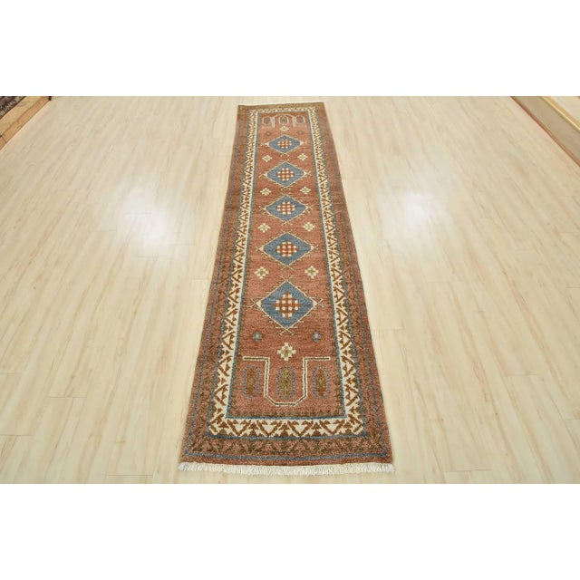 A tribal Caucasian Kazak runner hand-knotted with an all-wool pile on a cotton foundation. This oriental rug features...