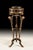Crafted with precision in Italy, this plant stand features three intricately hand-carved posts and a striking rub-through...