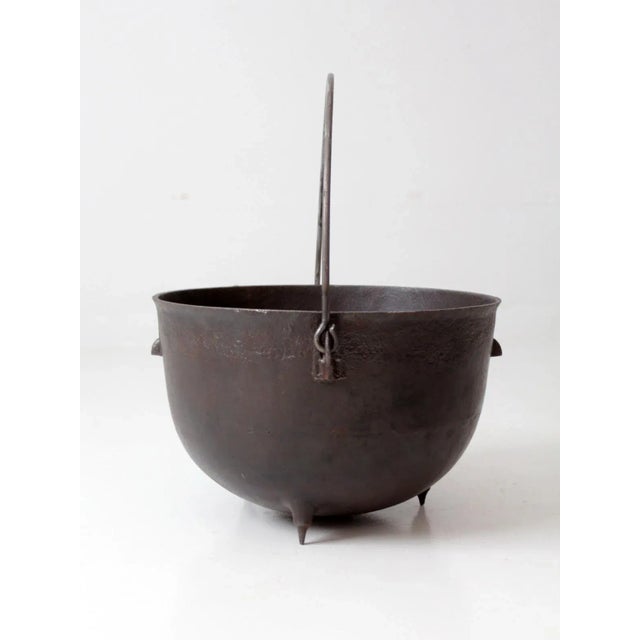 This is an antique cast iron cauldron. The large 15 gallon pot features a three-footed base and bail handle.