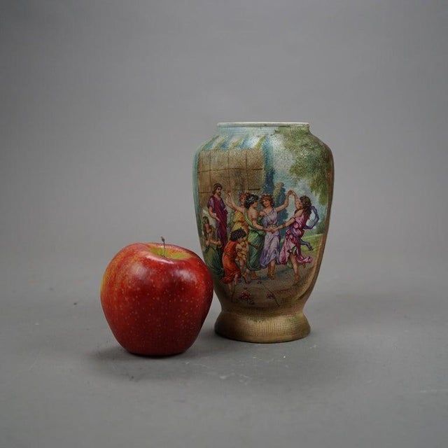 An antique German vase by Royal Bonn offers hand painted Classical genre scene with women dancing in a courtyard, maker...