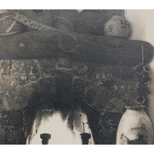 Early black and white still life photograph of a fireplace. The piece also documents the various items used to decorate...