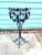 A tall vintage metal plant stand featuring an open scrollwork basket, slender tripod-style supports, and a decorative...