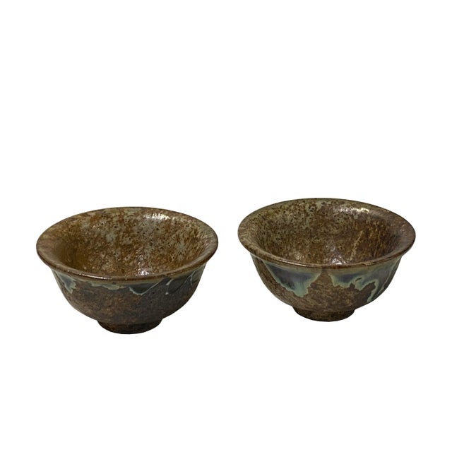 Discover the exceptional artistry in this pair of ceramic tea bowls. Meticulously handcrafted, each bowl showcases a rich,...
