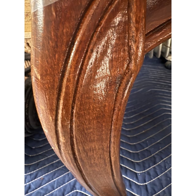 Elegant armchair with a carved wood frame and cream-colored damask upholstery. The chair has a scalloped backrest and...