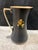 This is a vintage hand-painted ceramic pitcher featuring a matte black finish, red fruit illustrations and gold trim along...