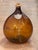 A blown amber glass demijohn with a shield reading "Eau de Vie 1881." Cork stopper with burlap collar.