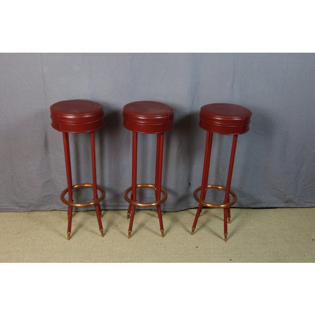 Bar stools with painted metal bases and copper leg bands; the seats are upholstered in burgundy vinyl. Very good...