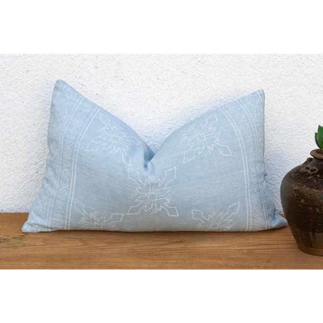 A four-petal flower-star medallion, hand block-printed in white, repeats across a soft powder blue linen ground on this...