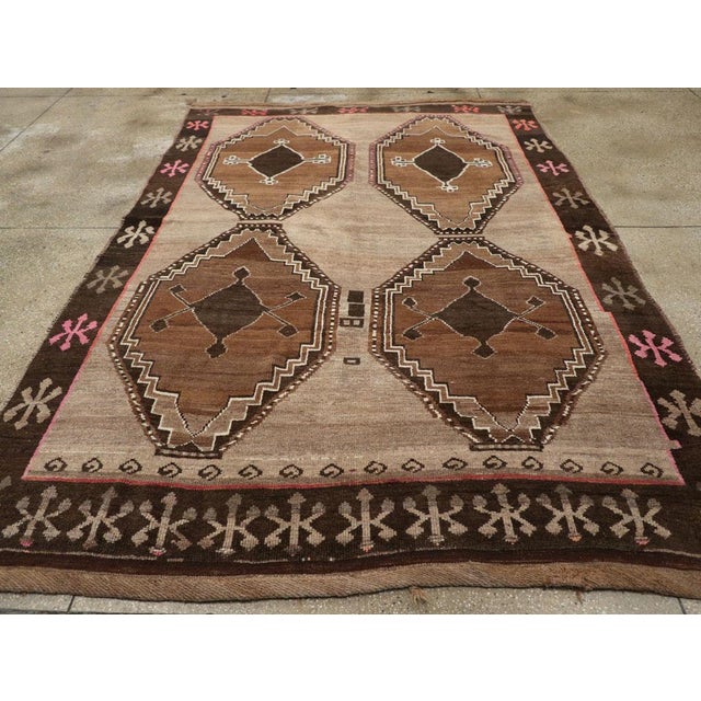 This mid-20th century Turkish Anatolian tribal carpet, measuring 7' 5" x 10' 4", presents a bold, symmetrical composition...