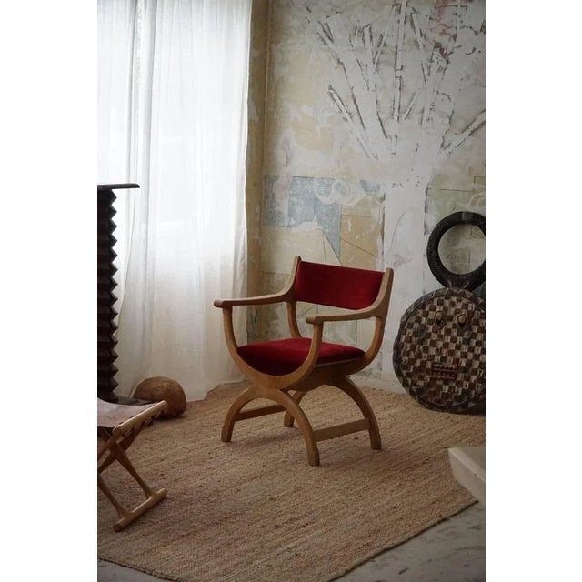 A fine and elegant armchair in solid oak upholstered in a decadent red velvet. Designed by henning (henry) kjaernulf for...