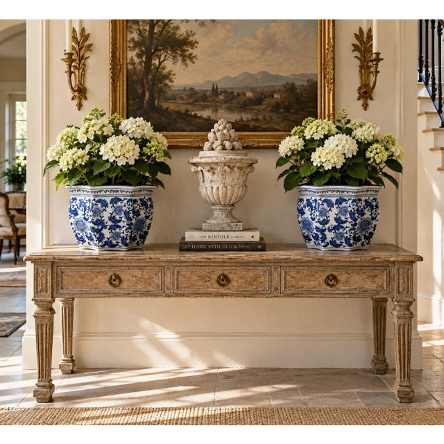 A classic pair of blue and white porcelain planters, rendered in a softly faceted, scalloped form that feels both tailored...