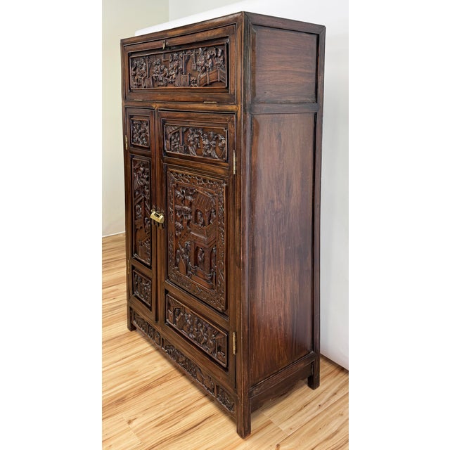 Antique early 20th century Asian cabinet featuring intricately carved wood with classic oriental scenes. Top door pulls...