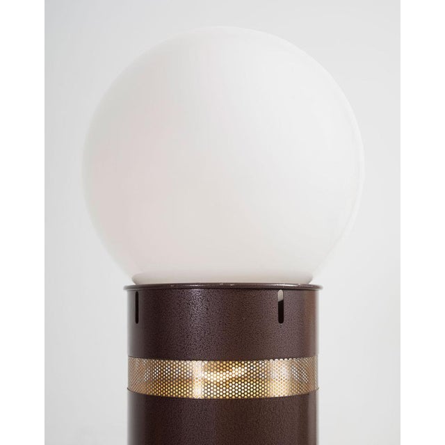 Oracolo floor lamp with a cilindical basement in brown lacquered metal with a pierced stainless steel section, and a blown...