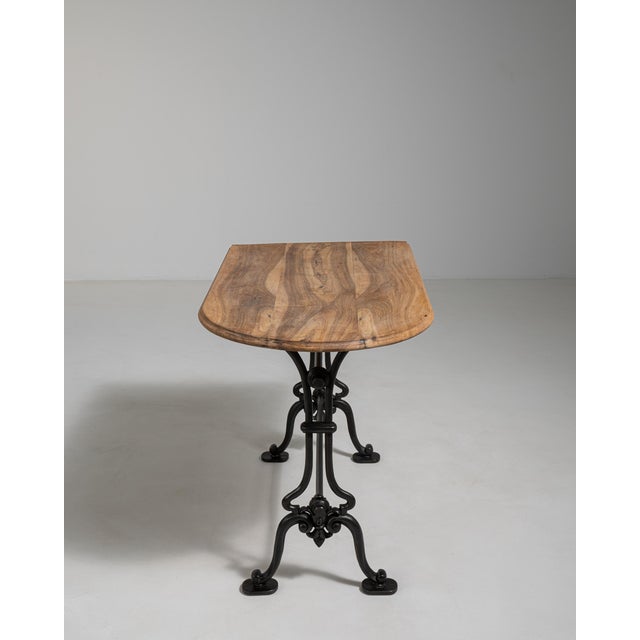 A classic French bistro table dating to the early 20th century, featuring a substantial cast iron base paired with a...