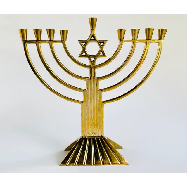 This vintage cast brass menorah features a traditional silhouette with a warm vintage patina.