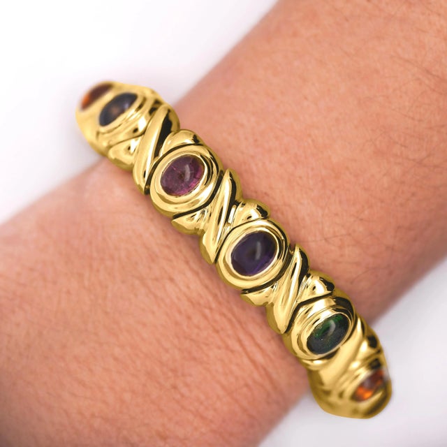 A vibrant vintage estate bracelet, crafted in solid 18K yellow gold, featuring a combination of bezel-set gemstones...