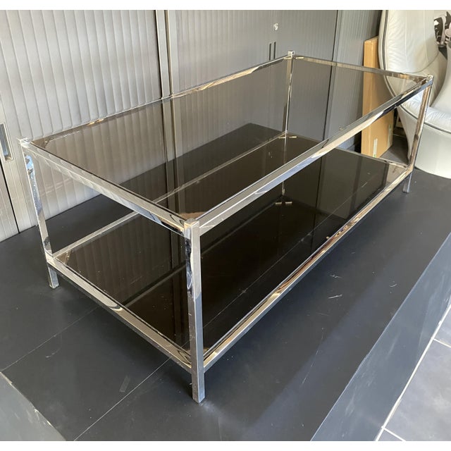 Square tubular steel frame, chrome in very good condition with minimal signs of wear. Smoked glass shelves with beveled...