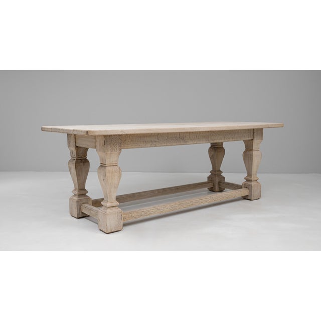 20th Century French Oak Dining Table. This solid oak dining table features a rectangular top supported by robust, turned...