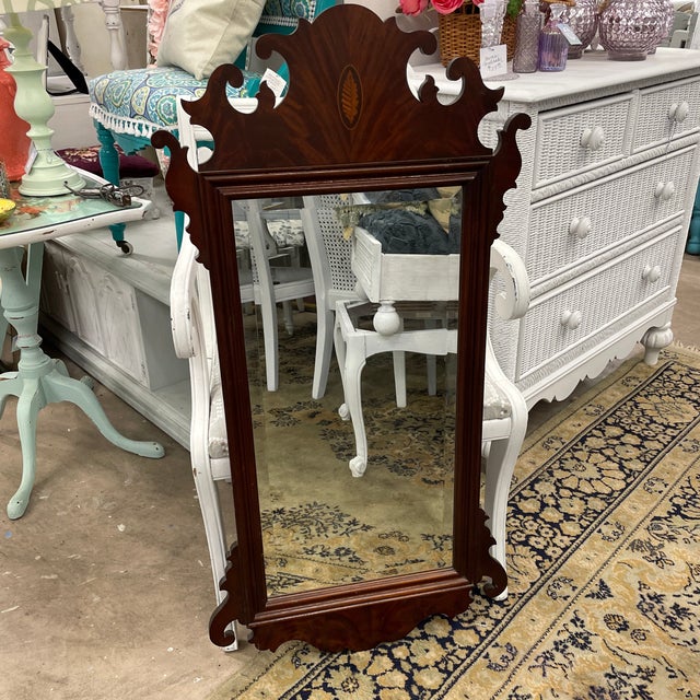 Vintage mahogany wall mirror has an ornate decorative scroll design along both the top and the bottom. The mirror itself...