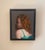 This oil on panel painting captures a figure in profile, draped in a delicate green garment that contrasts with the rich...