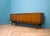 A mid-century sideboard by g plan (e. Gomme), dating to the 1960s, in a warm tola wood finish. the layout includes three...