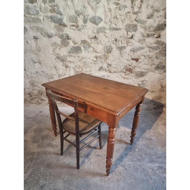 French oak desk table dating from the 1920s, featuring a simple and functional design with turned legs and two drawers....