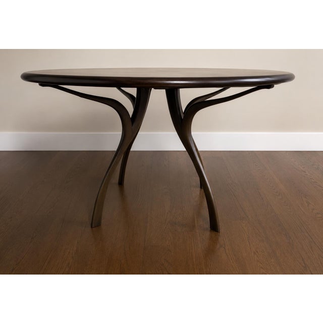 Custom sculptural round dining table sourced through Manifesto Design Group. Crafted from solid wood with a rich dark...