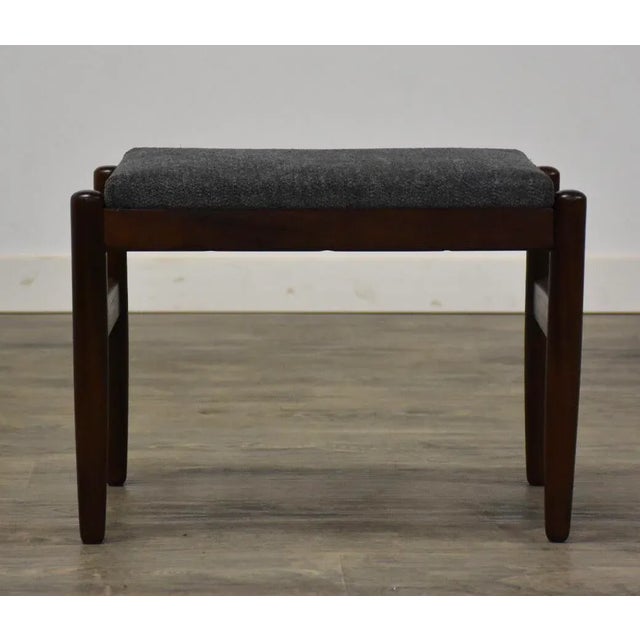 A mid century modern rosewood footstool or ottoman with grey fabric. 20.25” wide. 14.5” deep. 14.5” tall. This item...