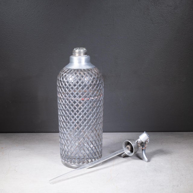 ABOUT An original Art Deco seltzer siphon bottle with pewter wire mesh. The metal dispensing head features stamped text...